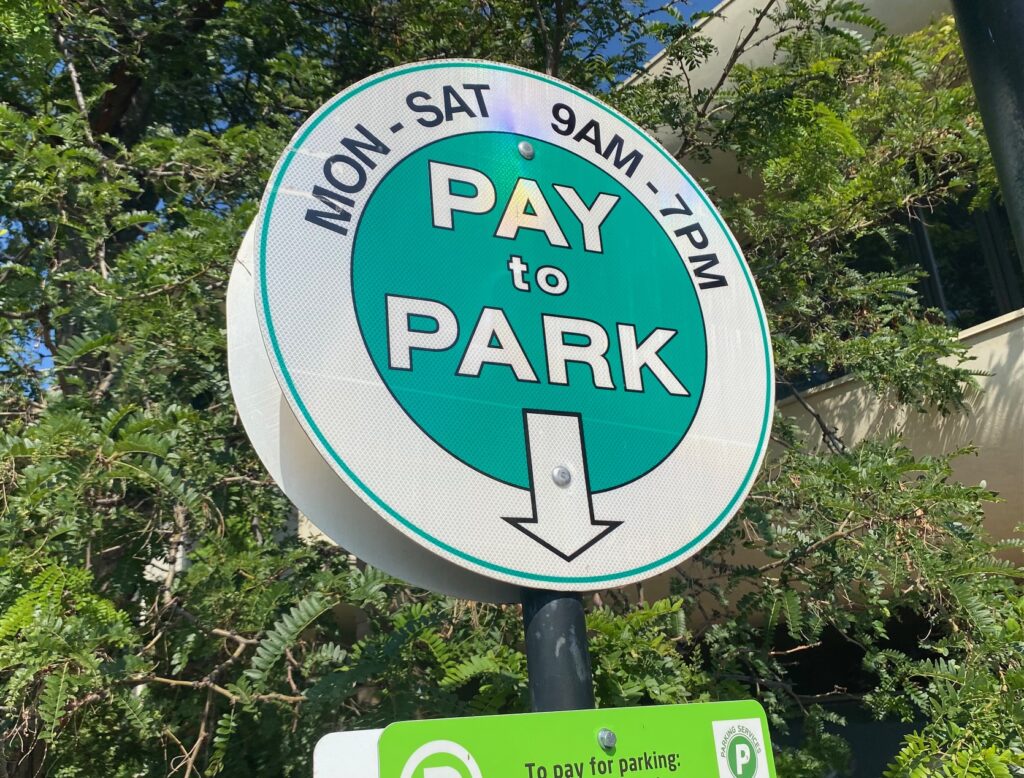 A parking sign stands in downtown Boulder. It reads "Pay to Park"